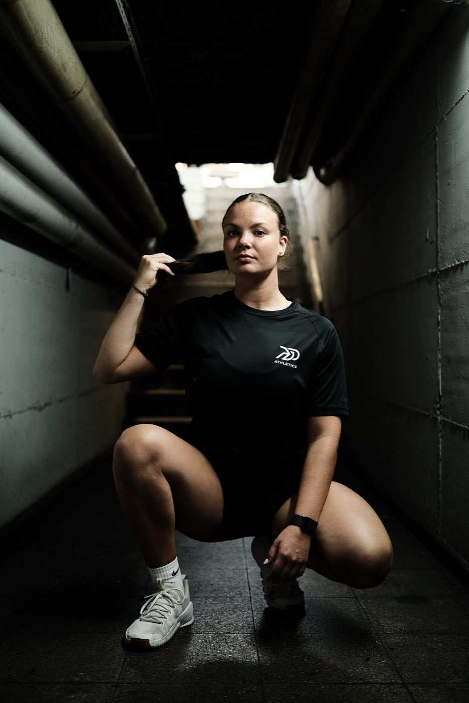 Athletin im schwarzen PGO-Athletics-Shirt in einem Betontunnel